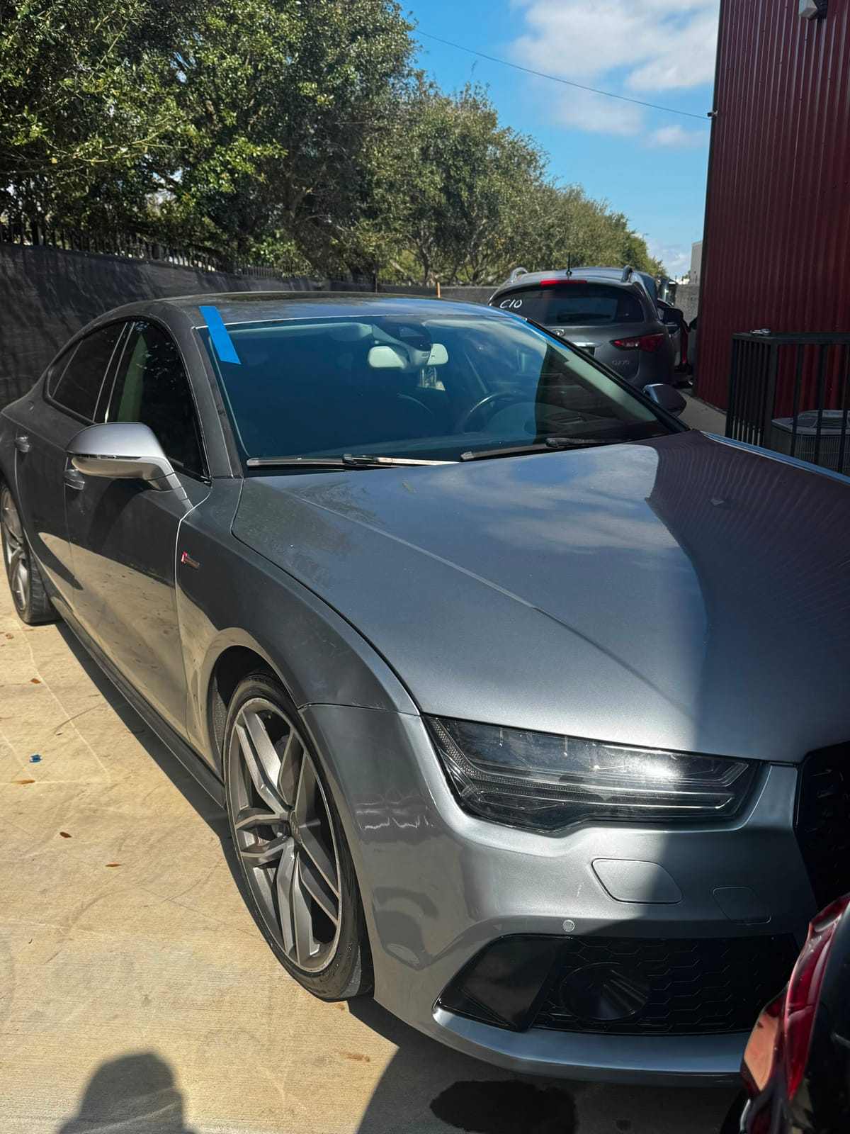 Gray Audi A7 Sportback with blue tape along the front glass during a windshield installation