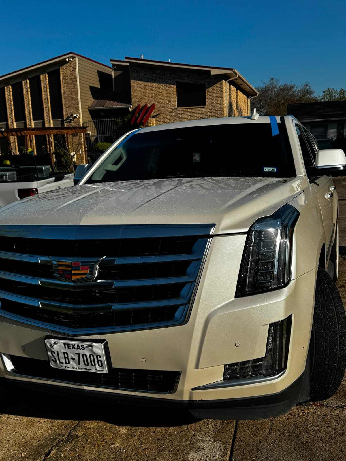 White Cadillac Escalade with blue tape along the windshield edge during a mobile windshield replacement