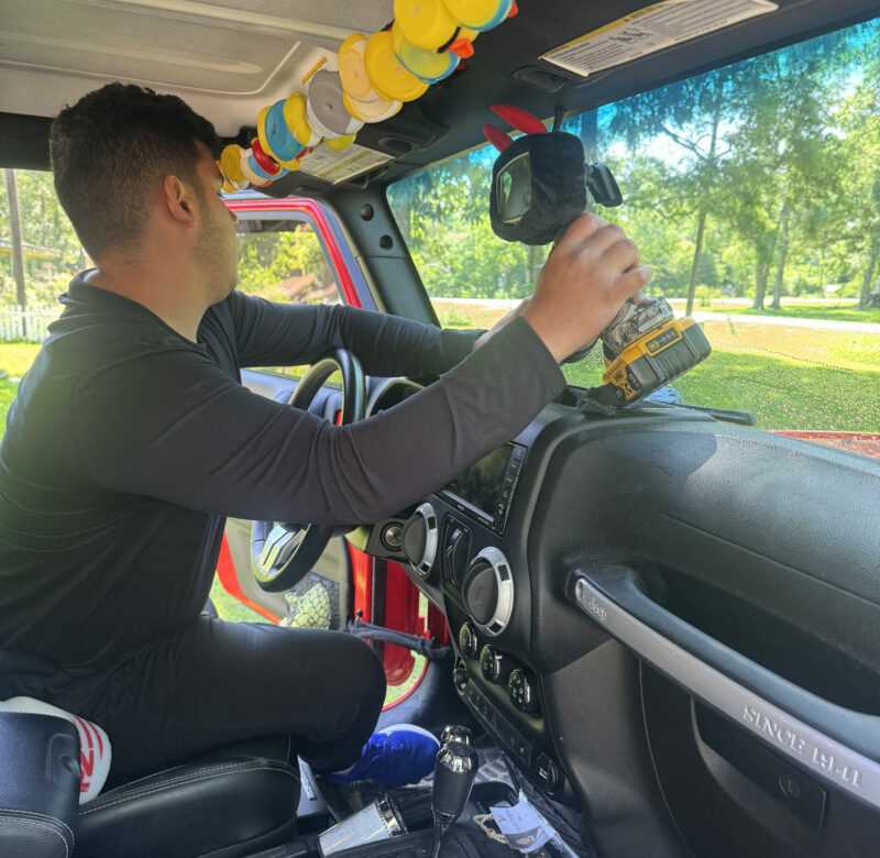 Technician working inside a vehicle cabin, dashboard and steering wheel visible